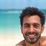 Flavio Cunha sorrindo com fundo de praia